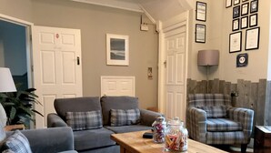 A living room with a sofa set, a wooden coffee table, and a plaid armchair. - St Bernards Guesthouse (Newquay)