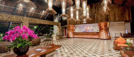 Um hall com piso xadrez, móveis de vime e luminárias pendentes com design de bambu.