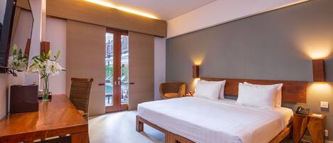 A modern hotel room with a large bed, wooden furniture, a desk, and a chair.