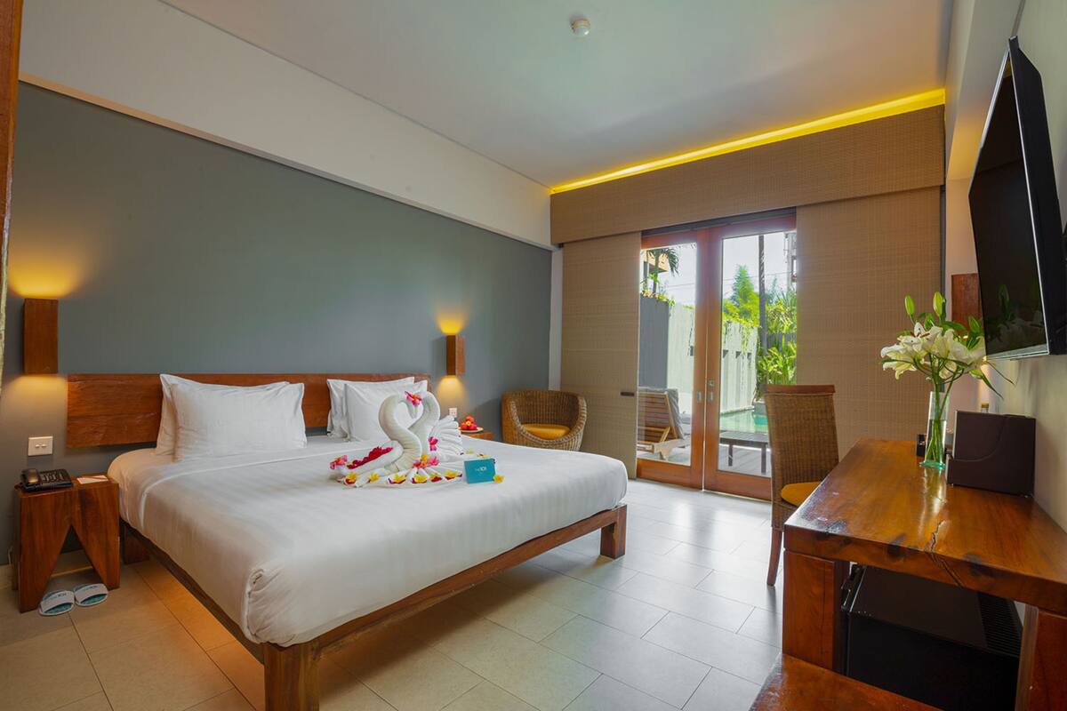 A hotel room with a large bed, a desk, a chair, and a television.