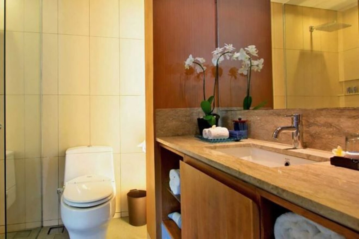 Un baño moderno con inodoro, lavamanos y espejo.