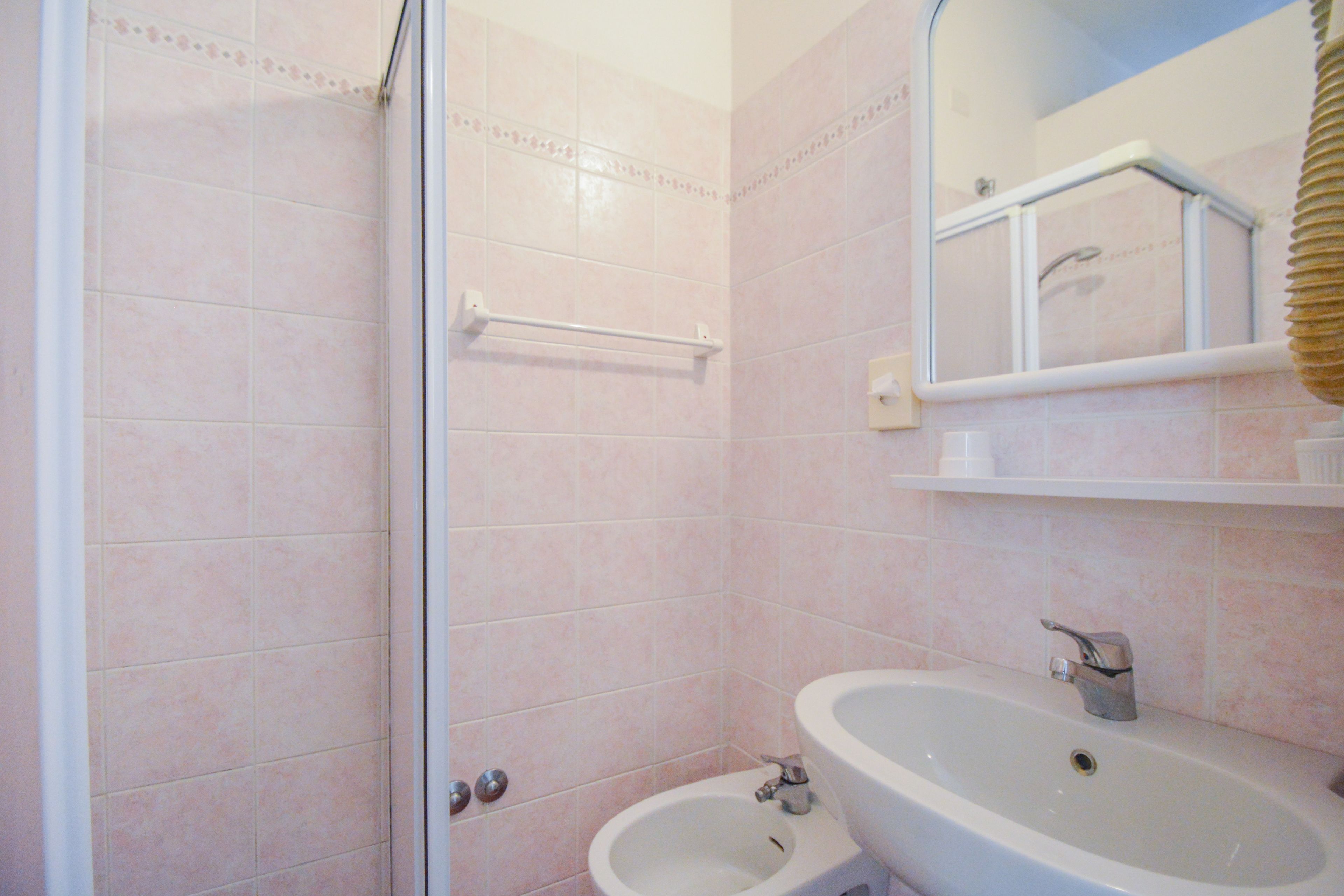 Ein Badezimmer mit Dusche, Bidet, Waschbecken und Spiegel.