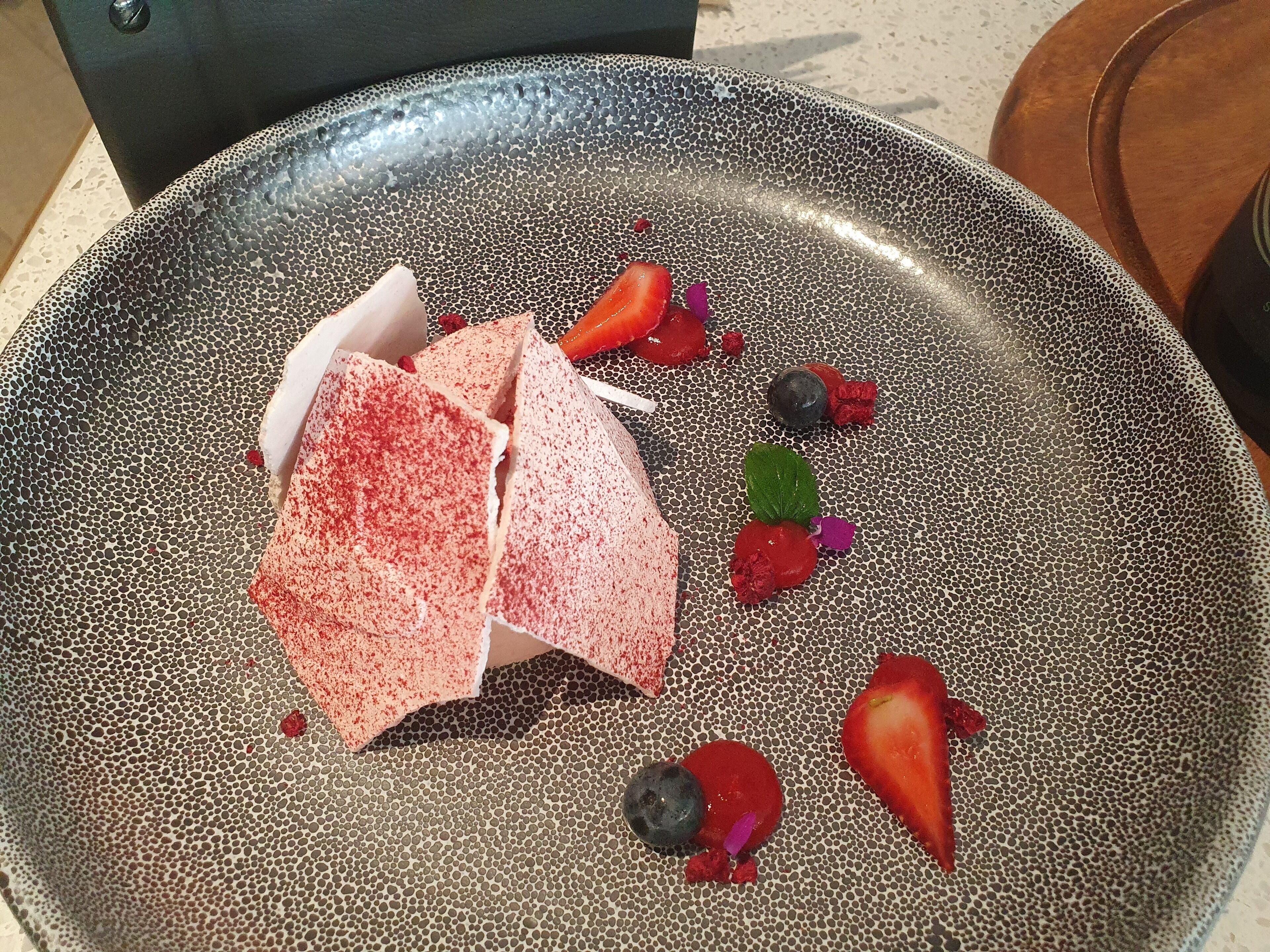 A dessert plate with various fruits and a textured bowl.