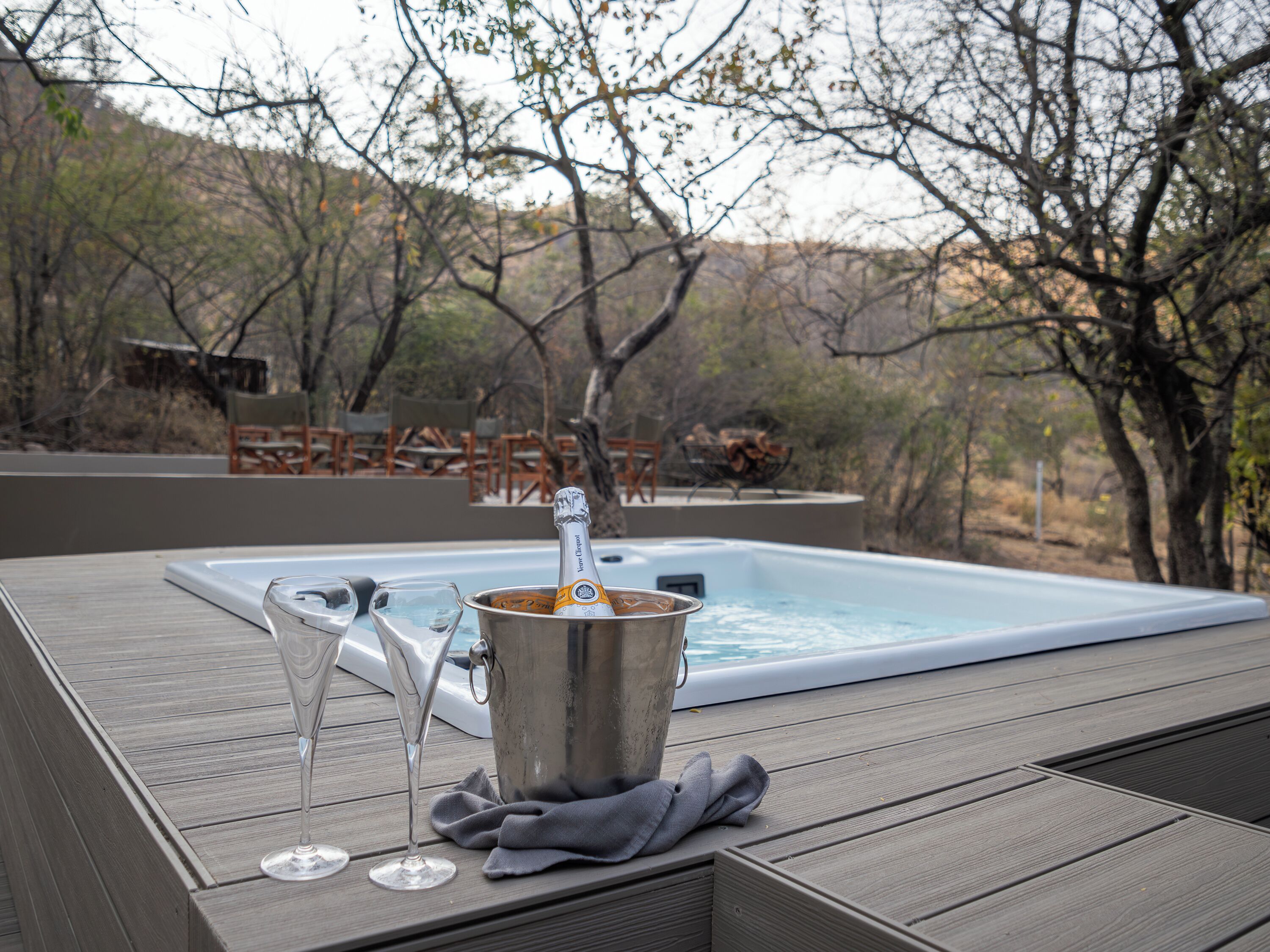 A hot tub with a bottle of champagne and glasses on a wooden deck.