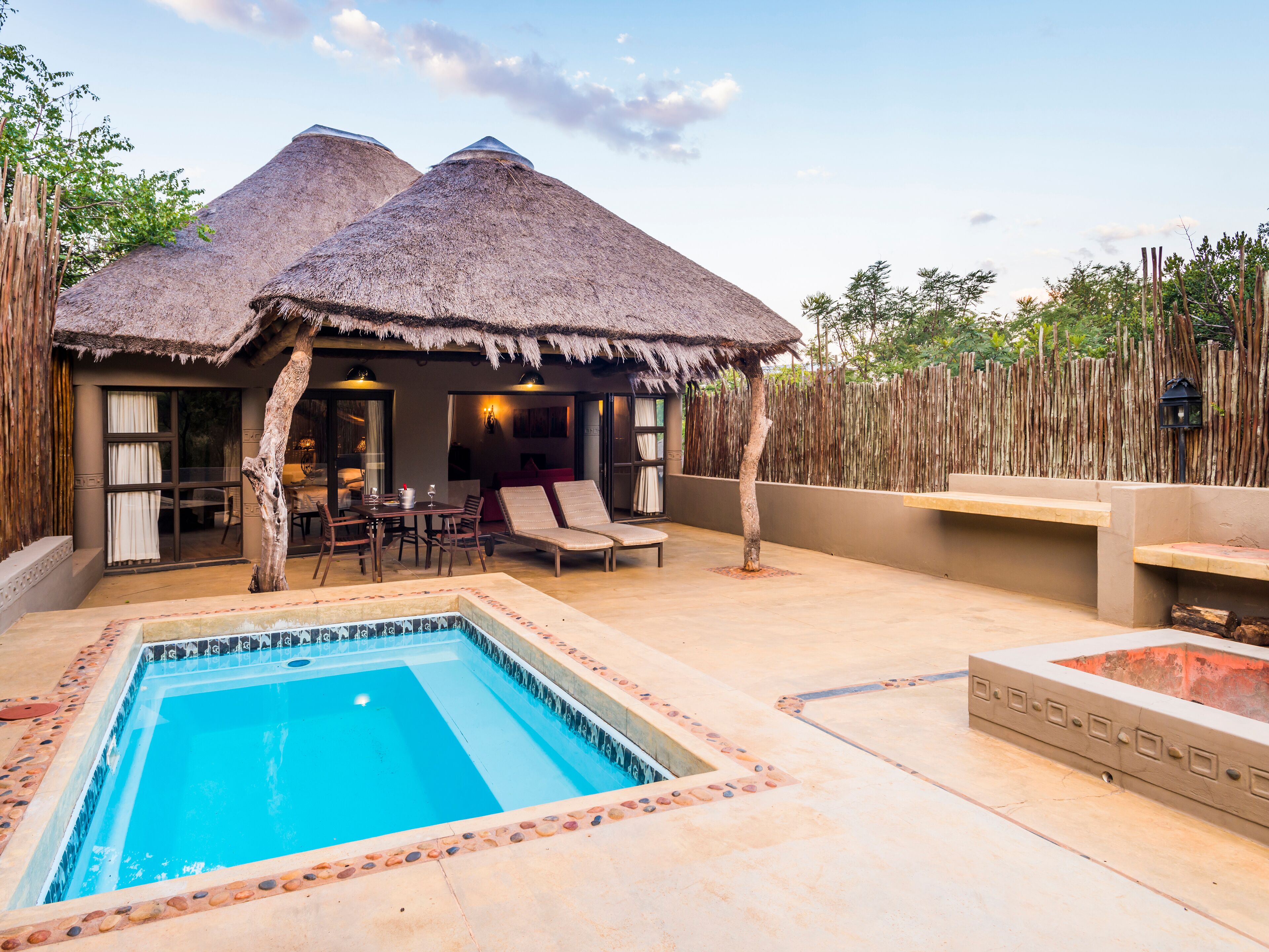 A pool area with a thatched-roof structure, lounge chairs, and a dining area.