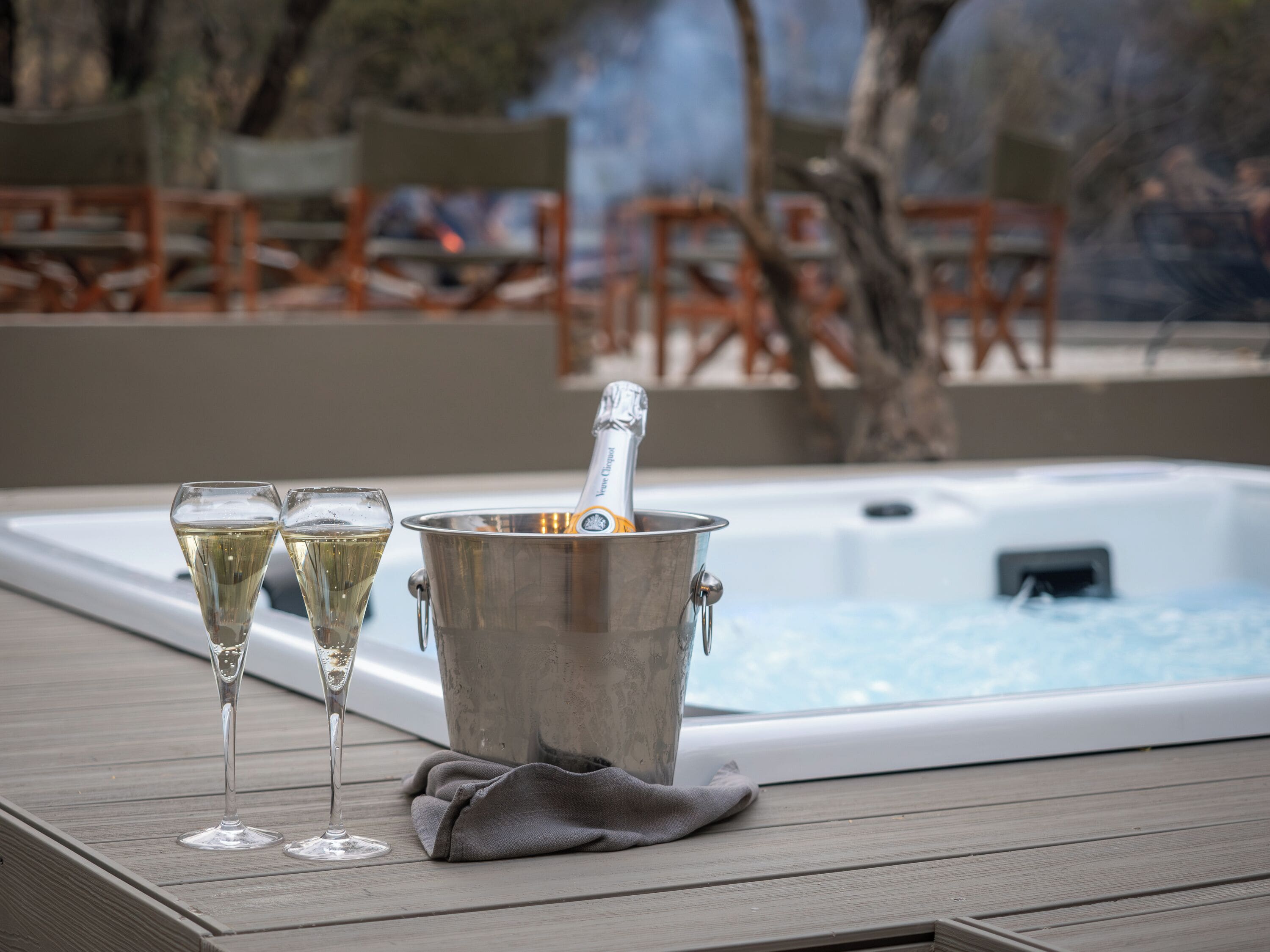 A hot tub with champagne glasses and a bottle on a wooden deck.