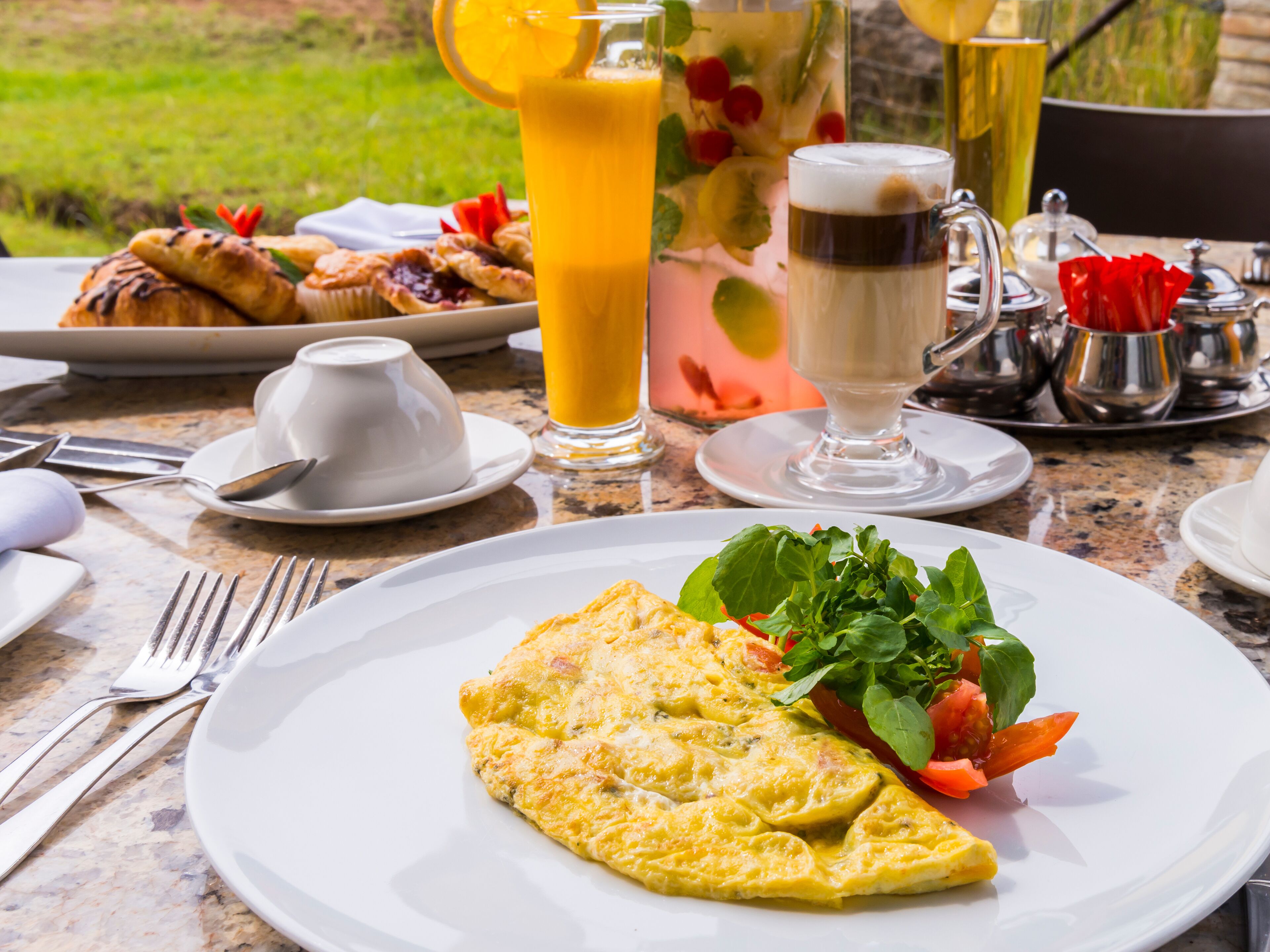 Un desayuno con una porción de tortilla, ensalada fresca y un vaso de jugo de naranja.