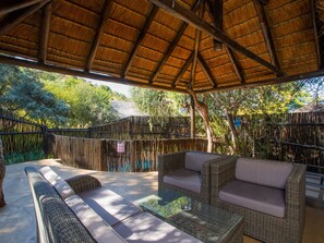 A covered outdoor seating area with wicker furniture and a thatched roof.