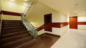A staircase with a wooden handrail and a door at the top. - Hotel Regent Grand (New Delhi)