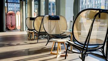 A modern interior with wicker chairs, a small wooden stool, and a glass partition.