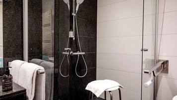A modern bathroom with a glass shower enclosure, a towel rack, and a toilet.