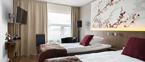 Habitación de hotel con dos camas, un televisor, un escritorio con computadora y un ventanal grande.