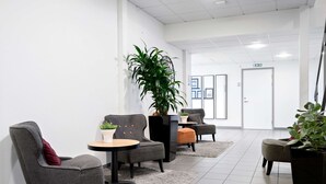 A modern waiting area with grey upholstered chairs, a small round table, and potted plants. - Best Western Hotell Ljungby (Ljungby)