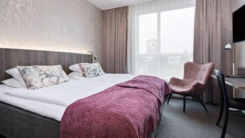 A hotel room with a bed, a desk, and a chair.