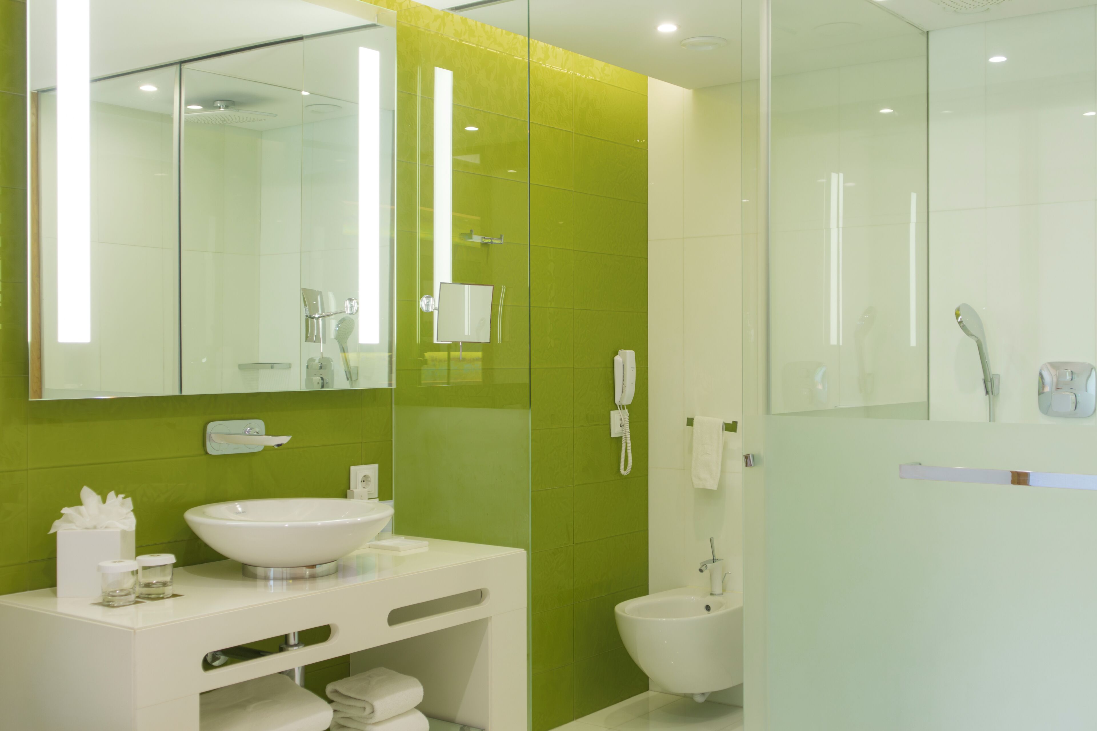 Une salle de bain moderne avec une douche à l’italienne en verre, un lavabo blanc et un grand miroir.