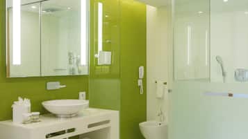 Une salle de bain moderne avec une douche à l’italienne en verre, un lavabo blanc et un grand miroir.