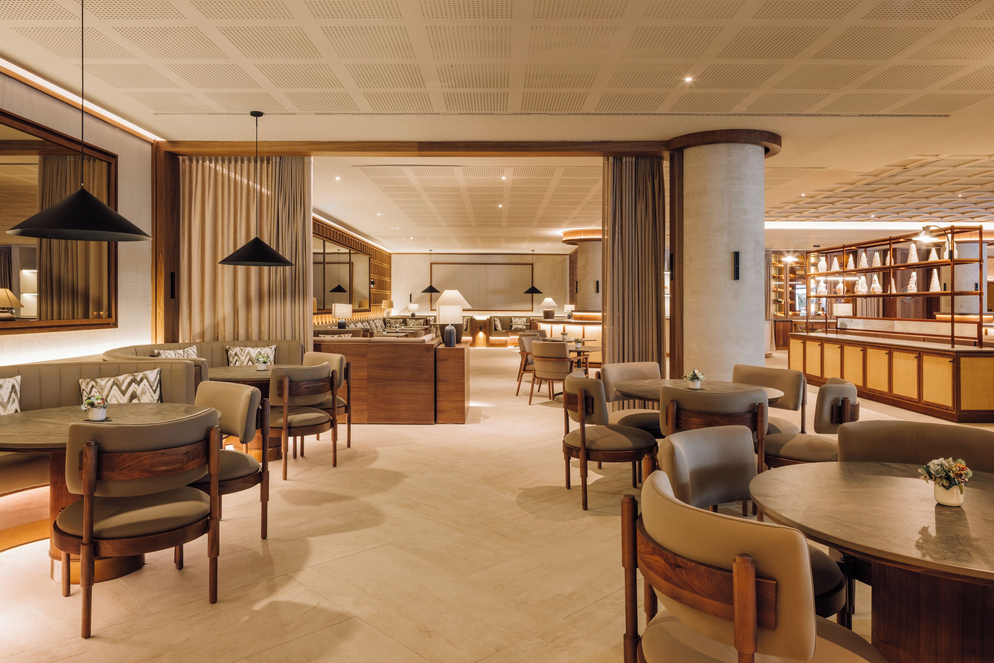 Eine moderne Hotellobby mit einer zentralen Rezeption, mehreren Sitzbereichen und einer Bar.
