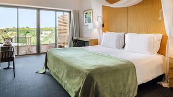 A hotel room with a large bed, a desk, a chair, and a view of the outdoors.