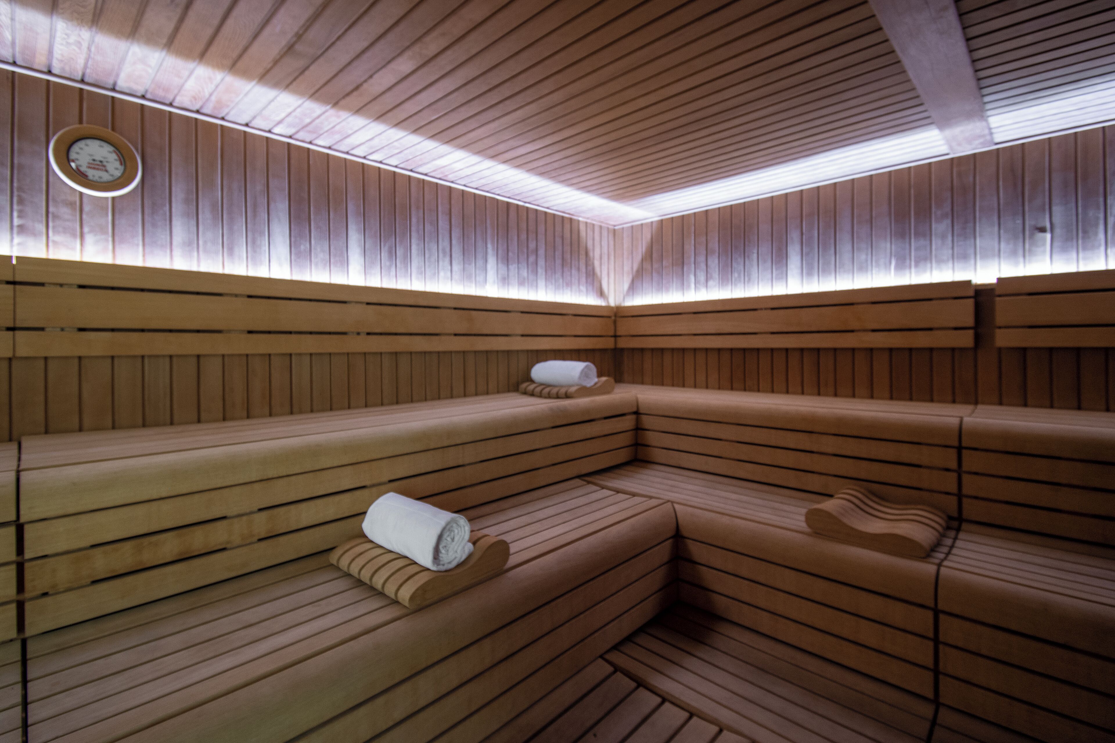 A sauna with wooden benches and a clock on the wall.