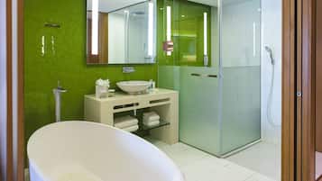 Un baño moderno con una bañera independiente, ducha con mampara de vidrio y tocador con espejo.