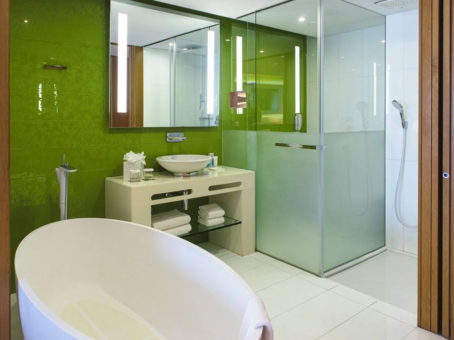 Un baño moderno con una bañera independiente, ducha con mampara de vidrio y tocador con espejo.