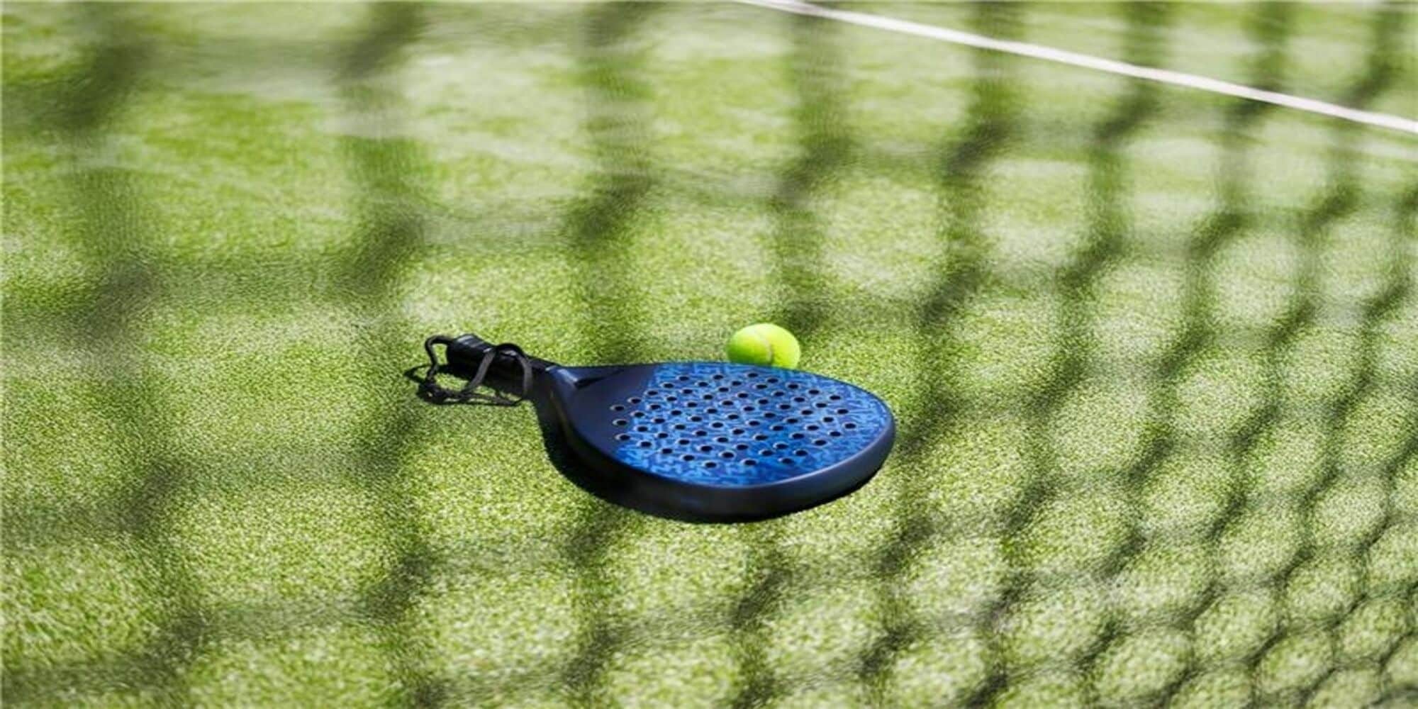 Een tennisracket en een bal op een groene ondergrond met een witte lijn, waarschijnlijk een tennisbaan.
