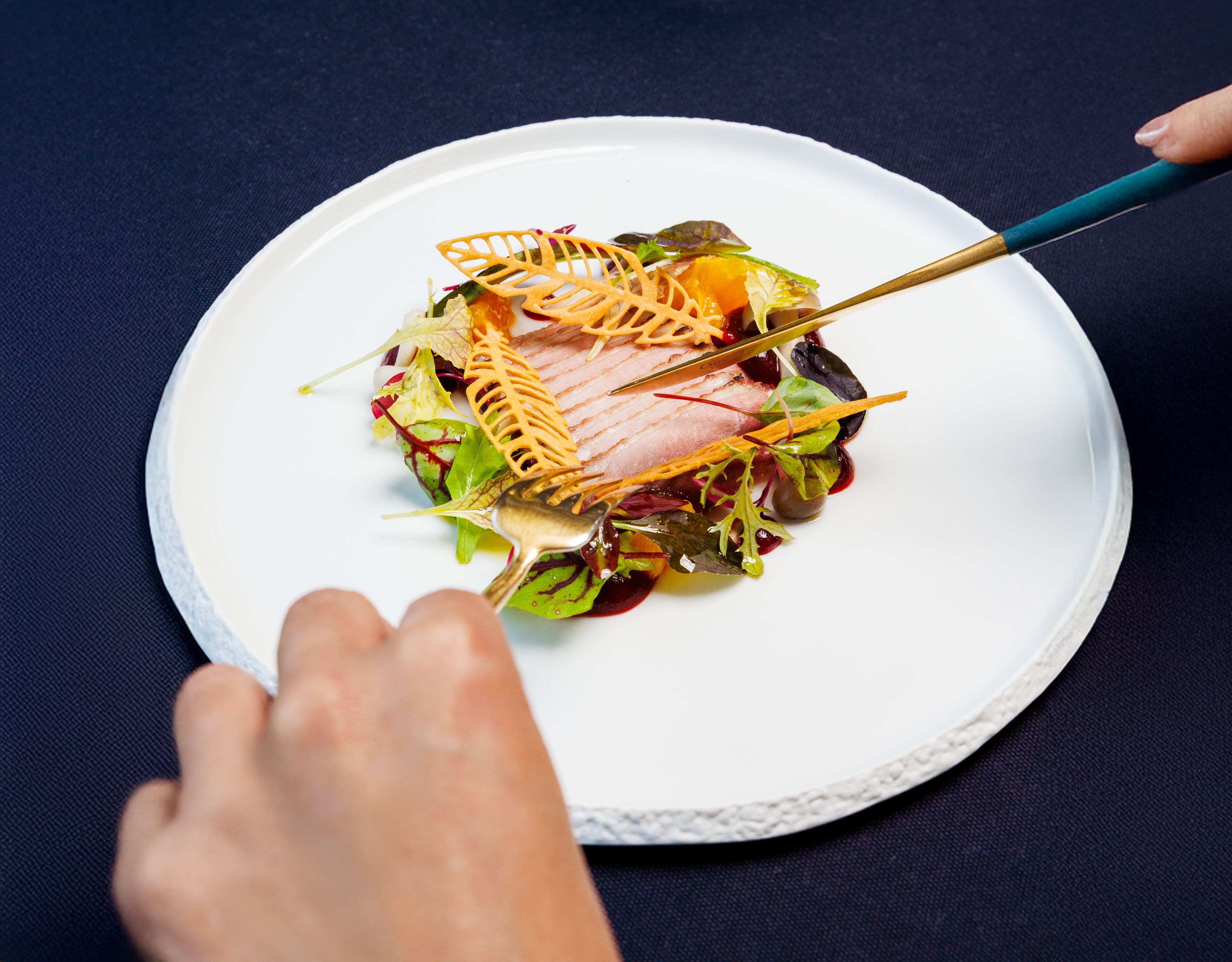 Une assiette blanche contenant un plat composé de viande et de légumes verts, le tout présenté sur un fond sombre.