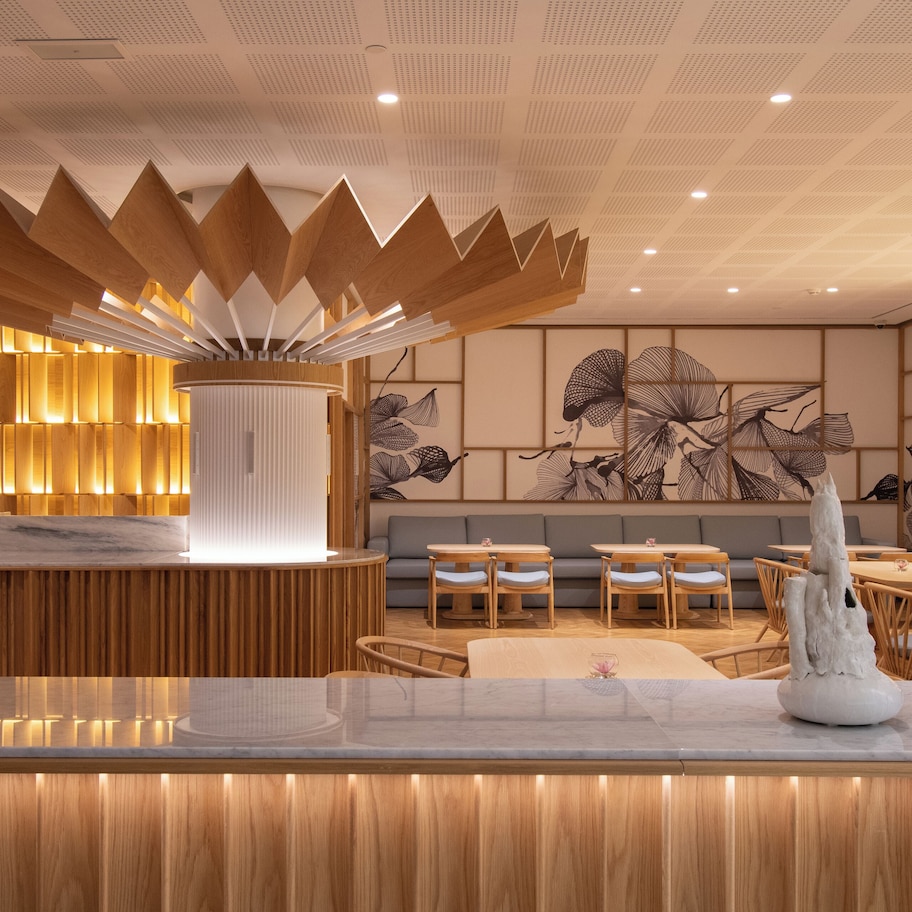 A modern interior with a wooden reception desk, seating area, and decorative wall art.