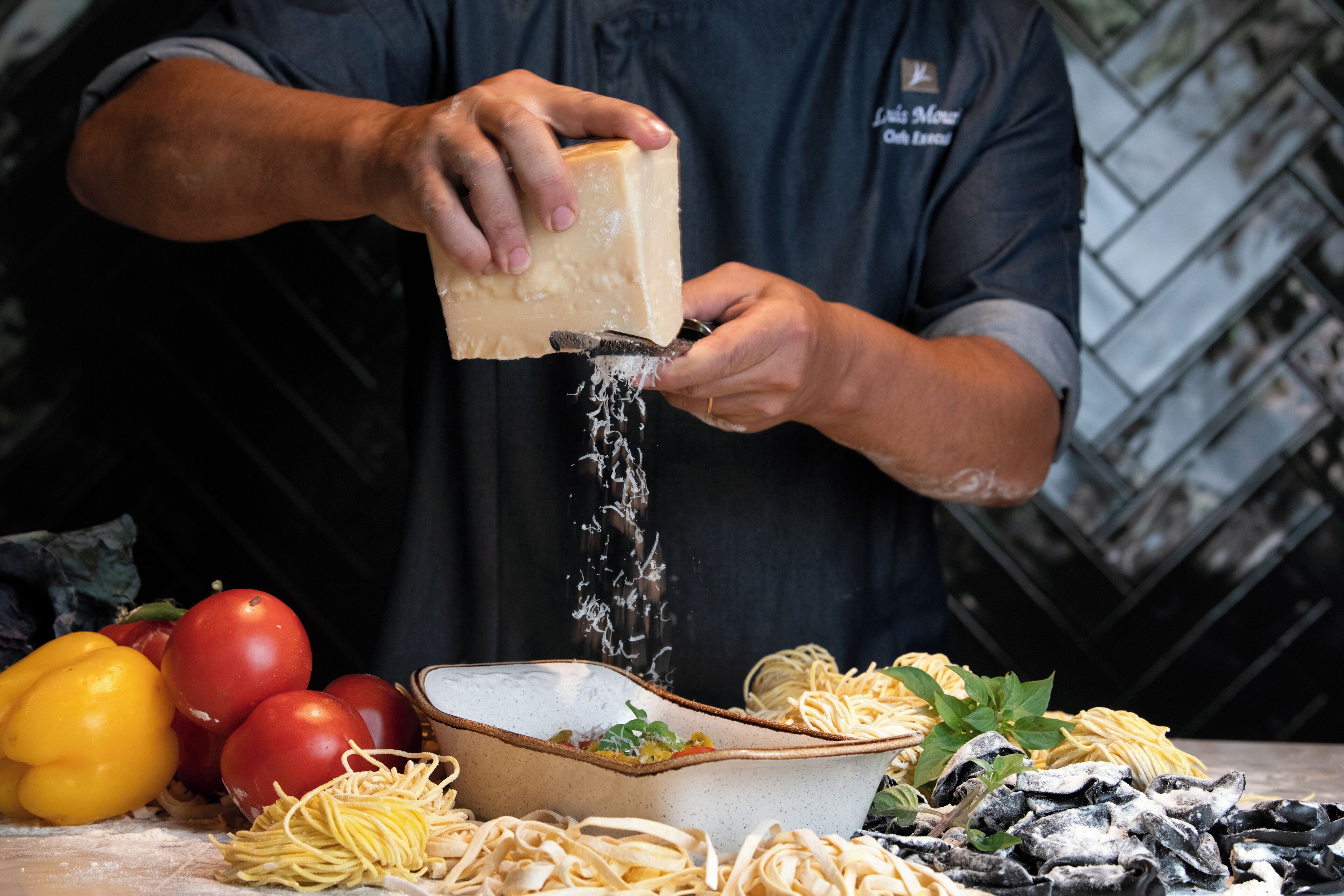 Una persona rallando queso sobre un plato de pasta.