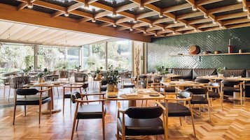 Un restaurante espacioso con suelo de madera, ventanas amplias y un diseño de techo tipo espiga.