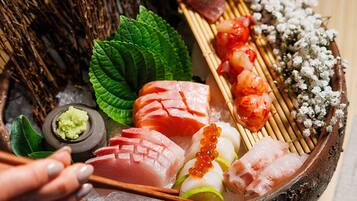 A variety of sushi and sashimi on a wooden tray with chopsticks, garnishes, and a small bowl of wasabi.