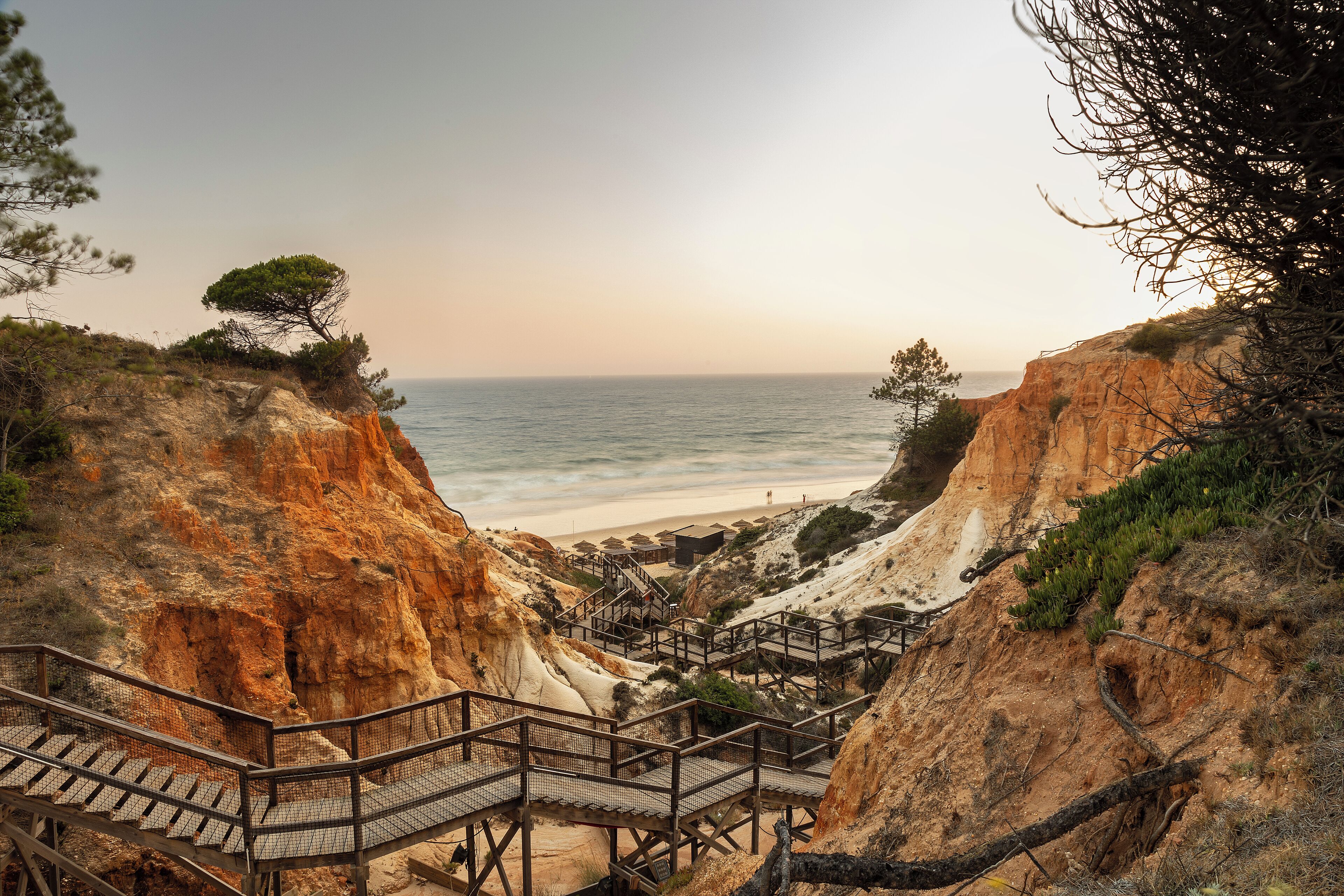 A coastal staircase leading to a beach area with a view of the sea.