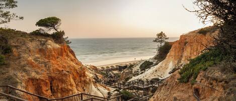 A coastal staircase leading to a beach area with a view of the sea.