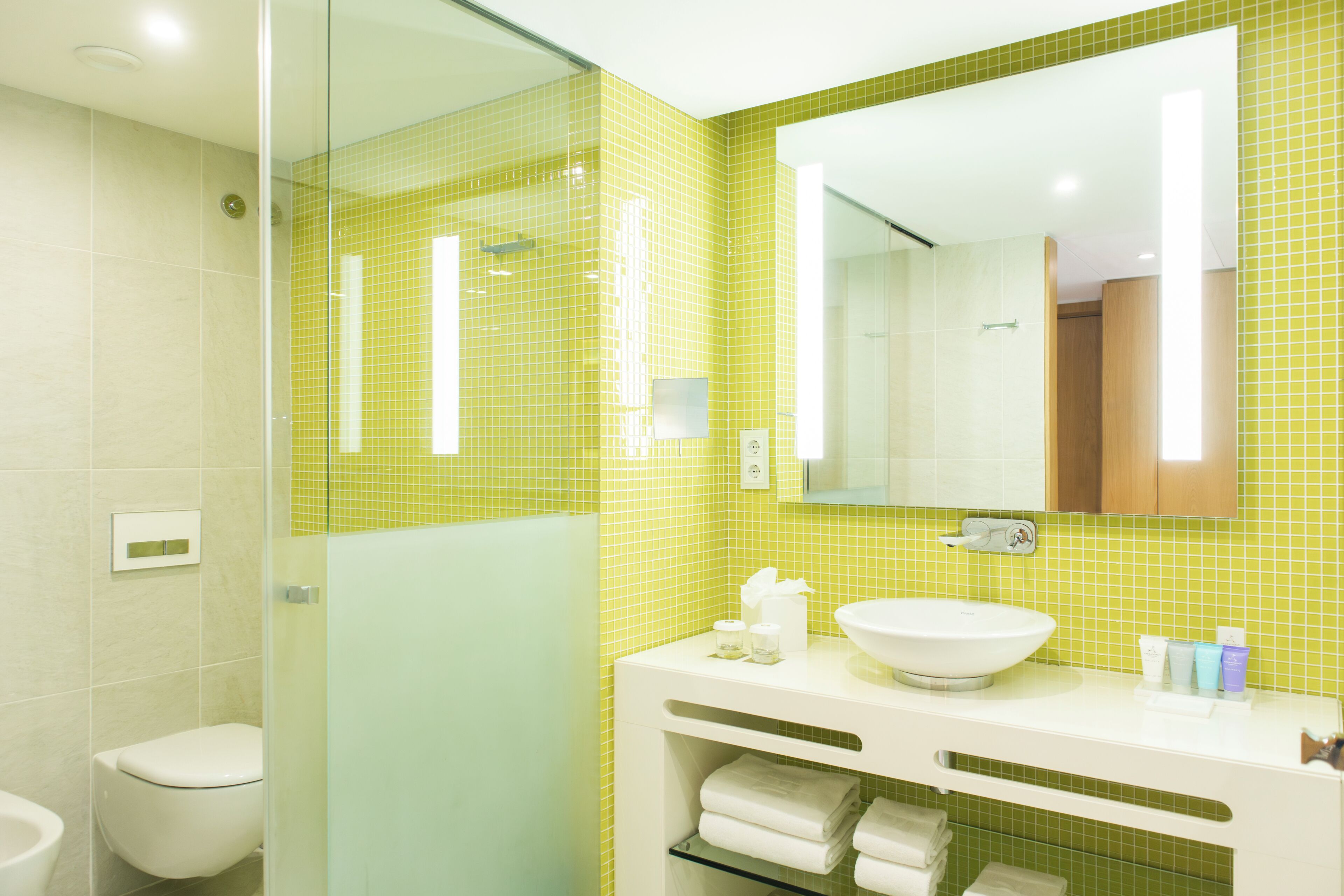A bathroom with a glass shower enclosure, a white sink, and a mirror above it.