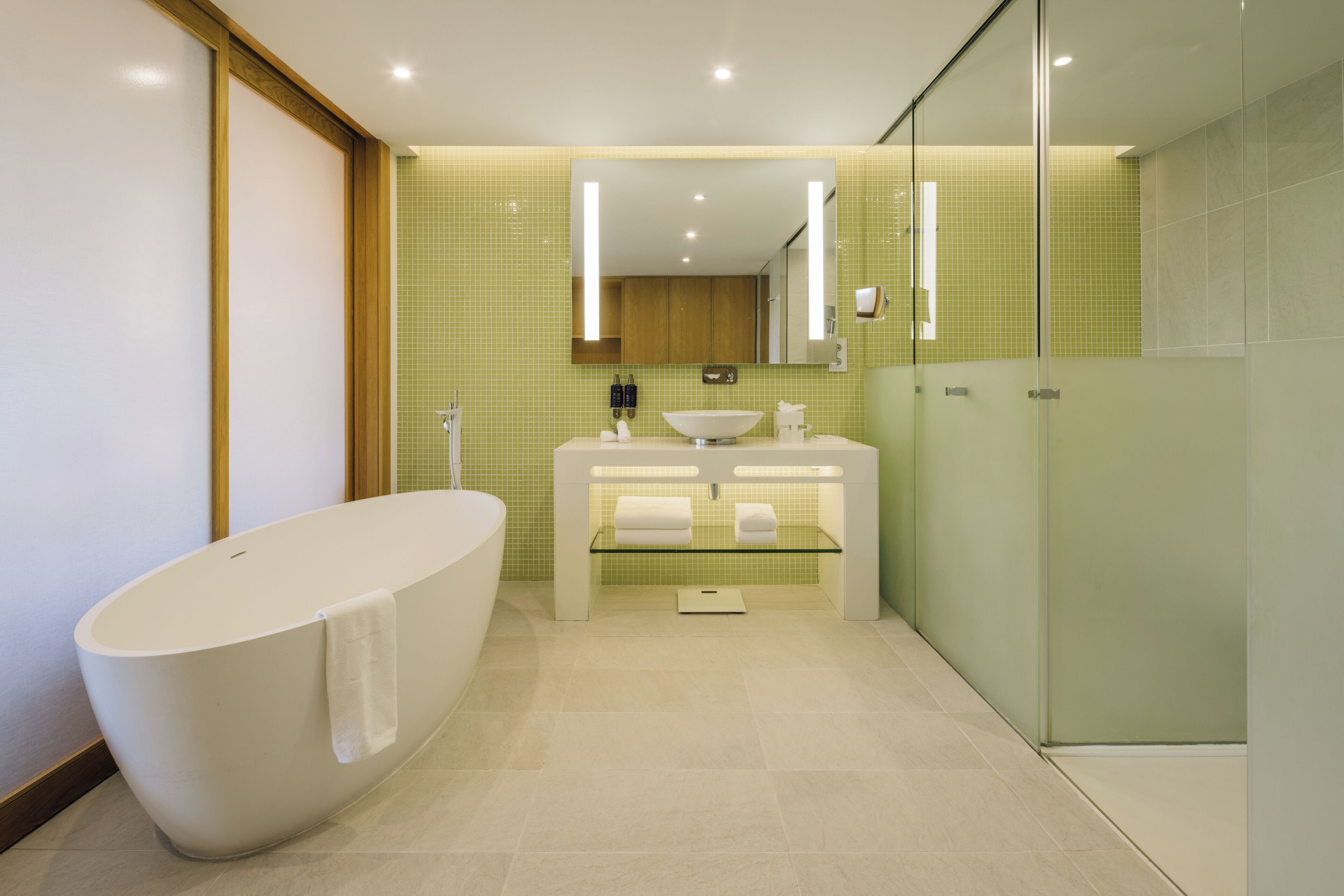 A modern bathroom with a freestanding bathtub, a glass-enclosed shower, and a vanity with a mirror.