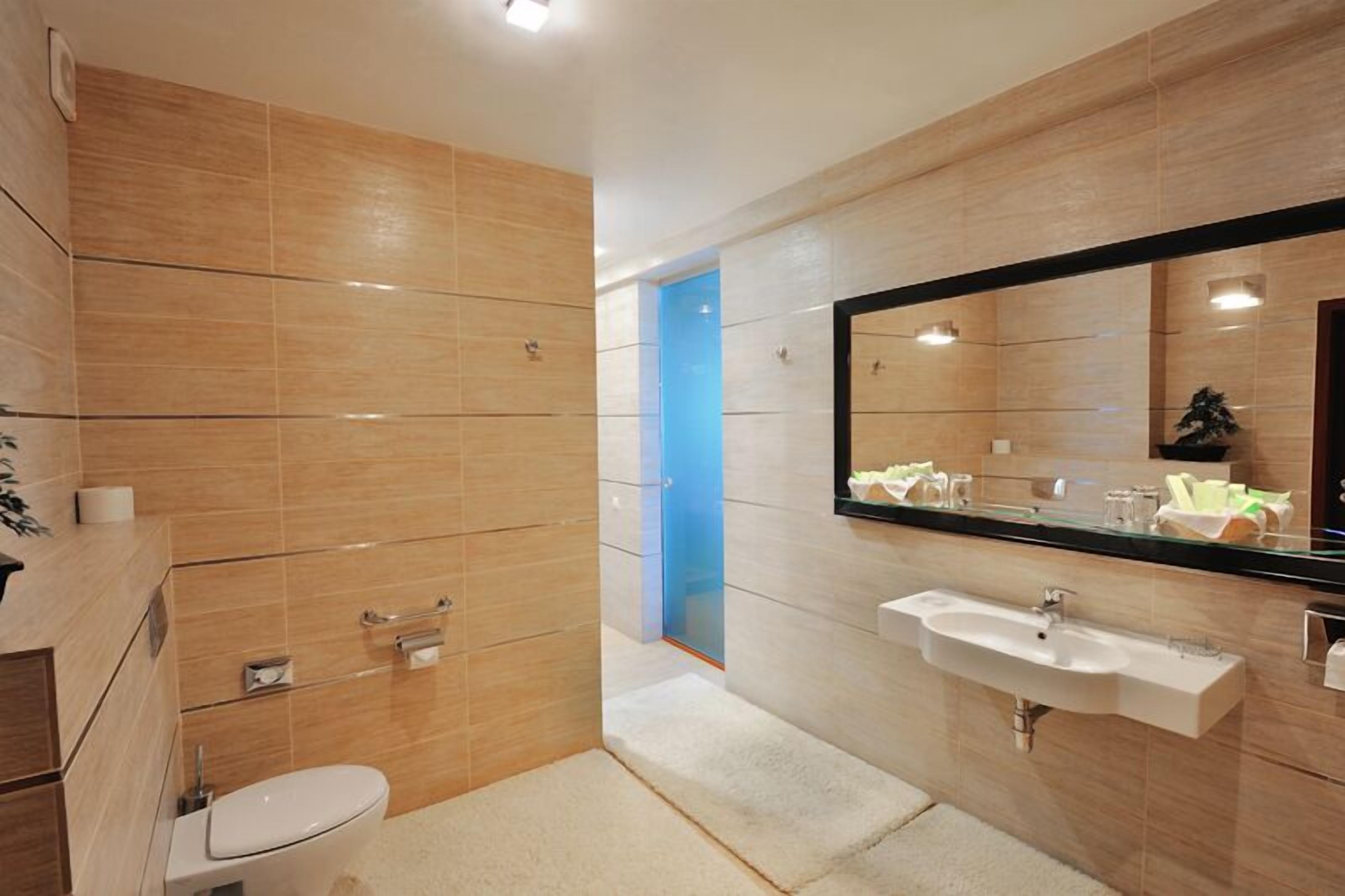 A modern bathroom with a toilet, sink, and mirror.