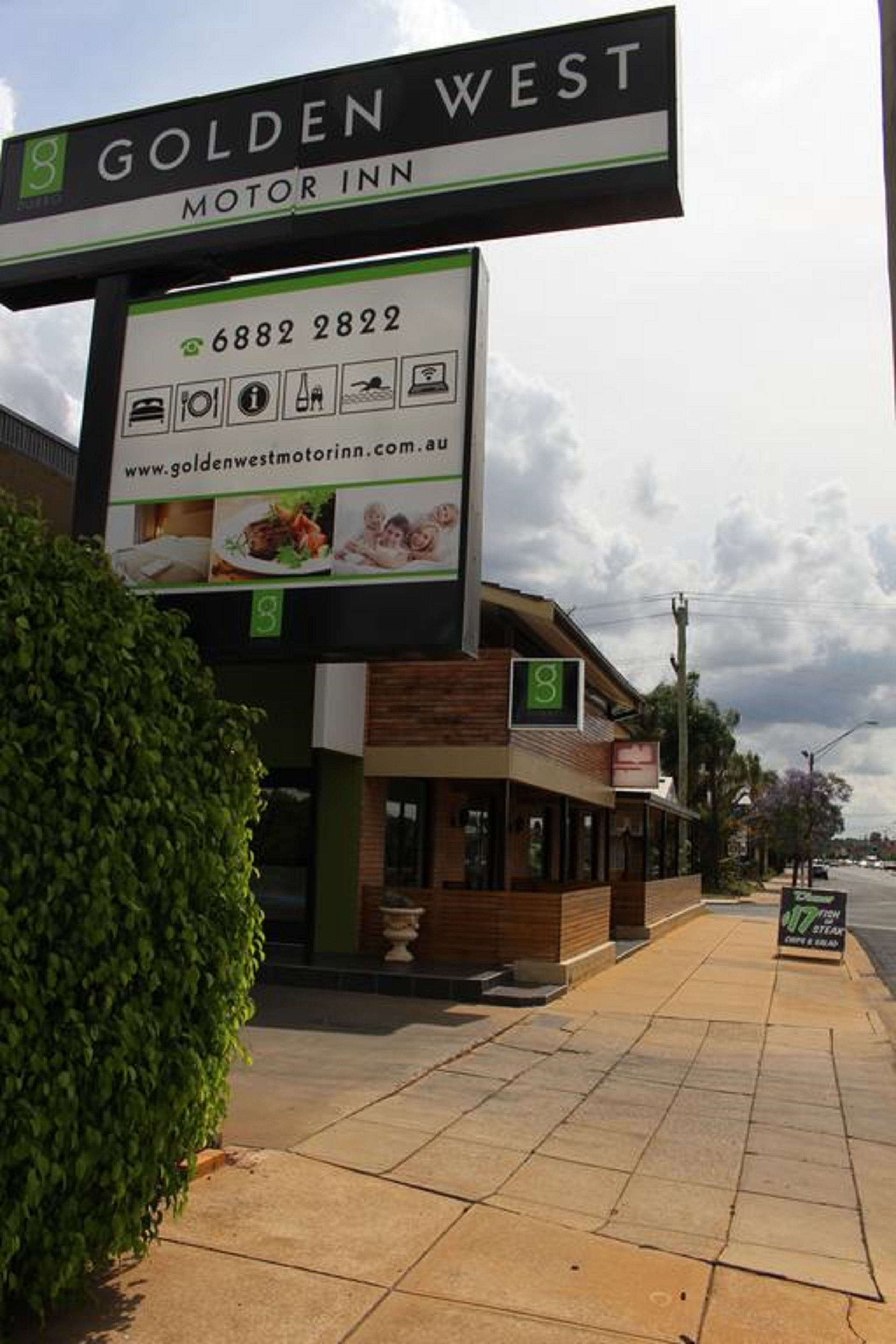 A hotel named Golden West Motor Inn with a signboard displaying amenities and a website URL.