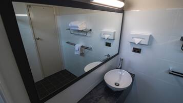 Un bagno moderno con uno specchio grande, un lavandino, un water e distributori di asciugamani.