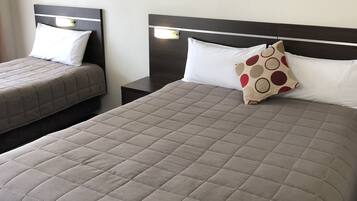 A hotel room with a large bed, two bedside tables, and two wall-mounted paintings.