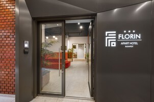 The entrance to Florin Apart Hotel in Budapest with a modern design, glass doors, and a reception area visible through the entrance.