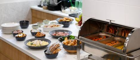 Un bufé con diversas opciones de comida, incluyendo carnes, verduras y pasteles.