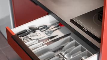 Una cocina de diseño moderno, con un lavamanos negro, una estufa integrada y un cajón con utensilios.