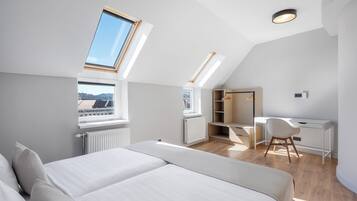 Una habitación moderna y bien iluminada con tragaluz, una cama, un escritorio y una silla.