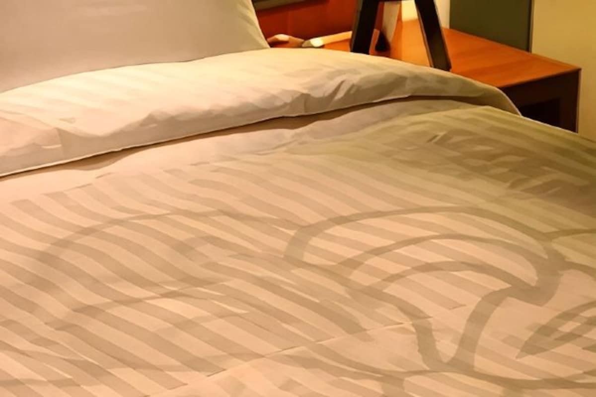 Un lit avec une couvre-lit à motifs et un oreiller.