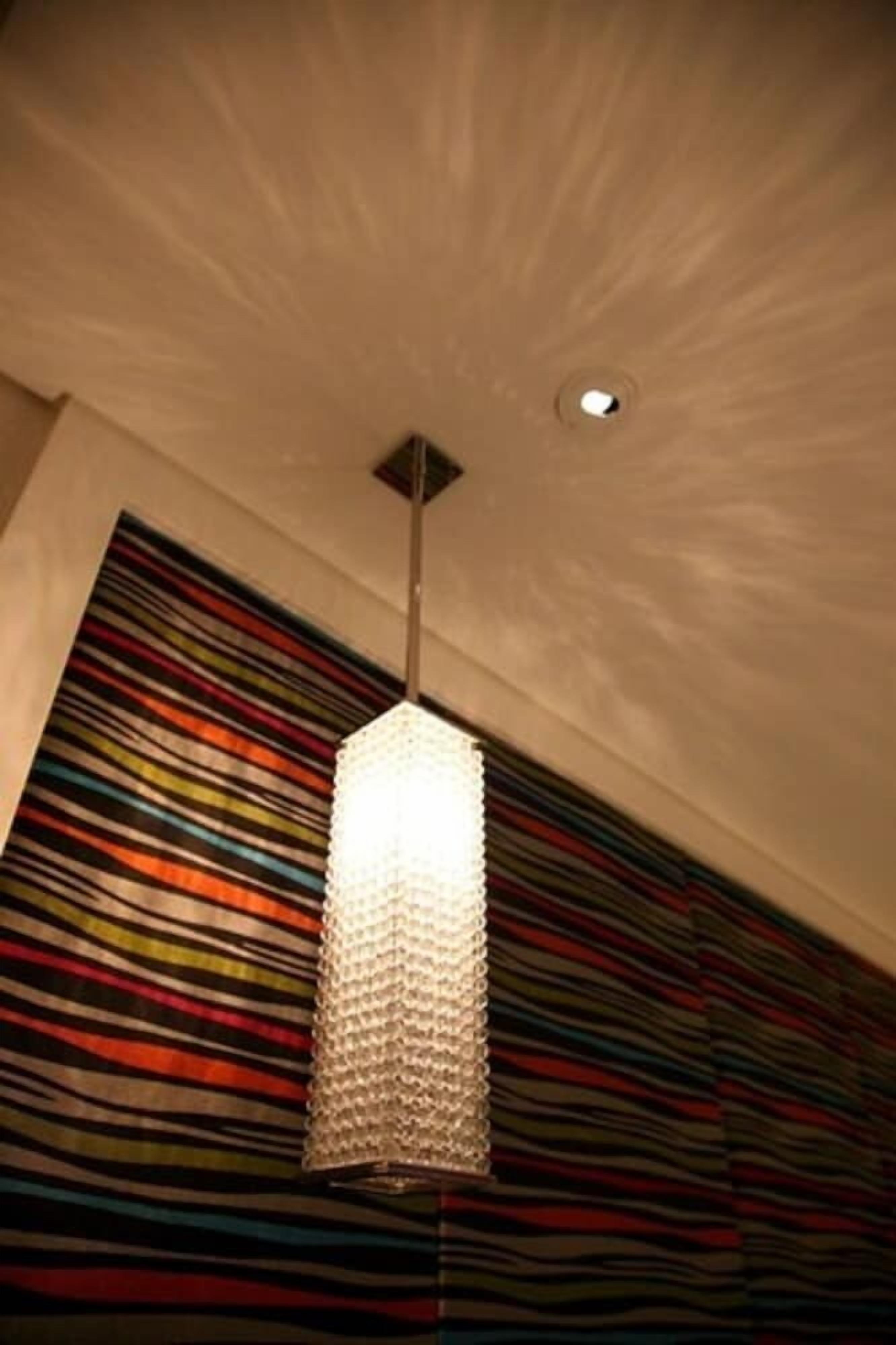 A room with a textured ceiling, a hanging light fixture, and a colorful striped wall.