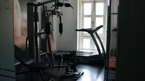 A gym with a treadmill, weight bench, and various exercise machines. - Sapphire Suites (Kolkata)