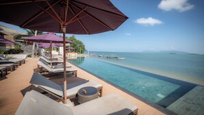 An infinity pool with clear blue water, lounge chairs, and umbrellas. -  Prana Resort Nandana (Koh Samui)