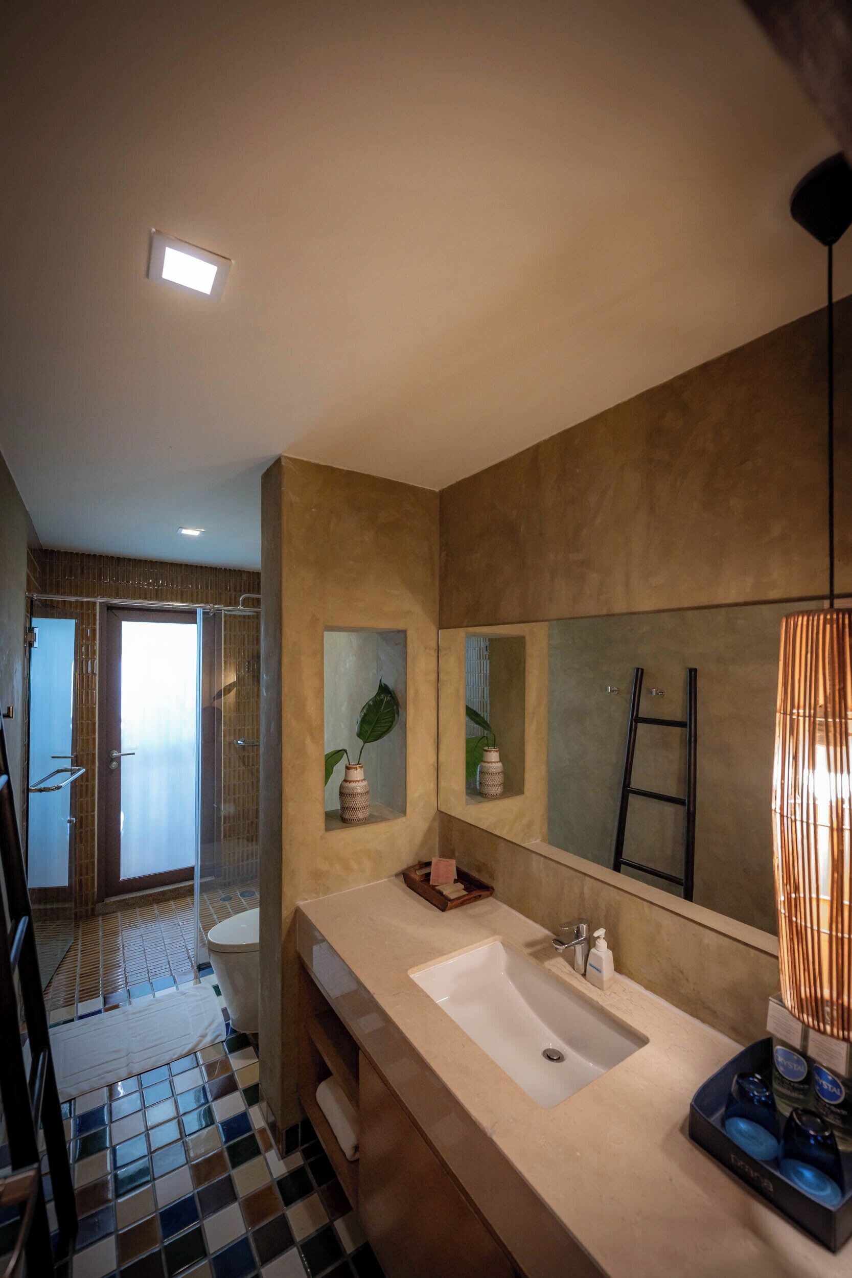 A modern bathroom with a large mirror, a sink, and a shower area.