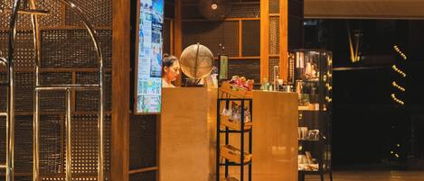 A lobby with a reception desk, a globe, and a cart.