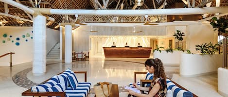 A spacious lobby with a high ceiling, a reception desk, and seating areas.